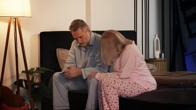 Wife comforting depressed husband while sitting on bed, care and support