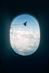 Breathtaking View from an Airplane Window, Looking Over White Clouds and Blue Sky in Bright Natural Sunlight