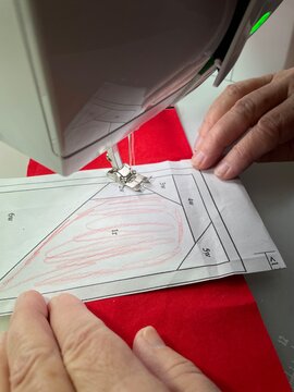 Precision foundation paper piecing (FPP) in action: sewing fabric pieces onto a marked paper template for accurate quilting results.
