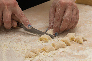 Hands cutting fresh homemade gnocchi on floured board, perfect for Italian cooking tutorials, recipe blogs, restaurant branding, artisanal food stories, and rustic cuisine visuals