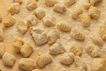 Fresh homemade gnocchi on floured wooden board, perfect for Italian food branding, recipe blogs, restaurant menus, cooking tutorials, and authentic rustic cuisine visuals