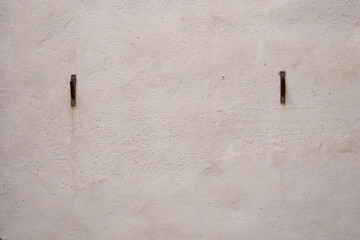 Minimal plaster wall with two metal hooks
