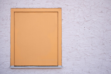Closed window with shutter on textured wall
