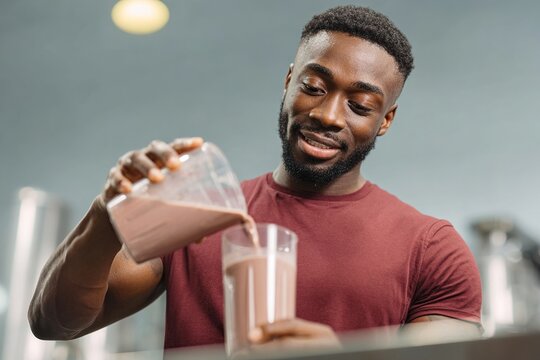 Fit black man pouring protein shake into a glass for a healthy lifestyle