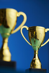 close up of gold trophies against blue background