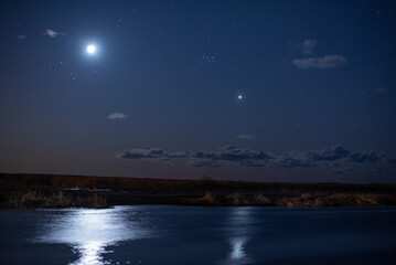 Bright moon and star over calm river at night. © Anna