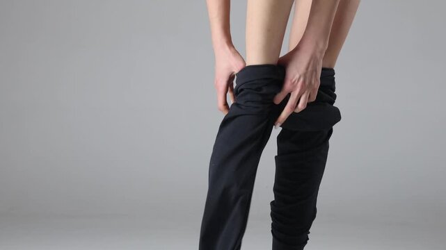 4k video, studio shot of a woman putting on leggings, adjusting fit and posing, fashion and activewear concept on a neutral background.