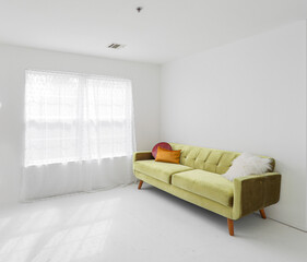 Minimalist living room interior with green sofa, white walls and soft natural window light