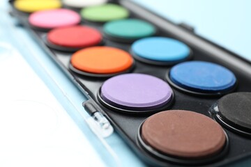 Watercolor palette on light blue background, closeup