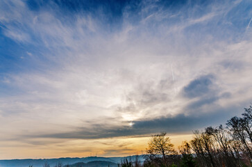 Dramatic sky with wispy clouds and distant hills at sunset