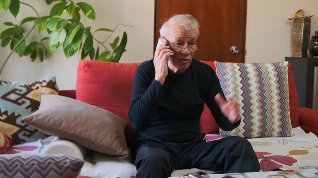 Senior Calls Attentively - Elderly Person Talks Vividly - Senior Individual Engages In Animated Discussion - Elderly Caller Actively Uses Gestures To Communicate Clearly During Mobile Chat Indoors