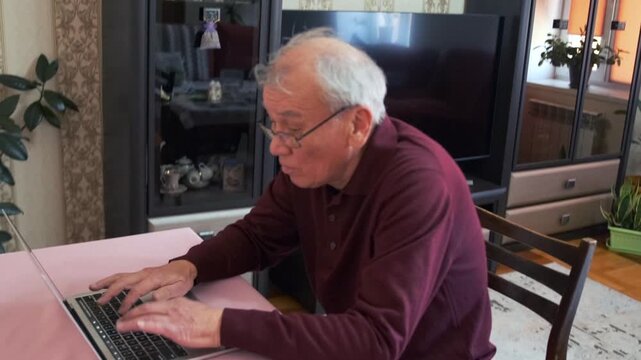 Older Man Concentrating On Email At Desk - Senior Man Focused On Composing Email At His Home Workspace - An Aged Man Carefully Typing Email While Sitting At His Home Office Desk With Concentration
