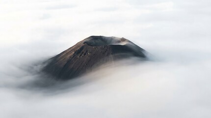 Volcano crater rising above sea of dense white clouds at sunrise