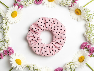 Delicate pink polka dot scrunchie surrounded by white daisies and pink carnations