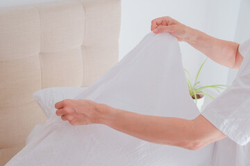 Woman changing bed linen in bedroom, home textile care, laundry, housekeeping