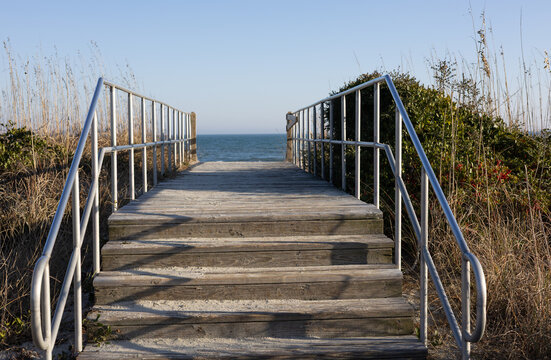 Wooden beach access boardwalk with stairs and railing