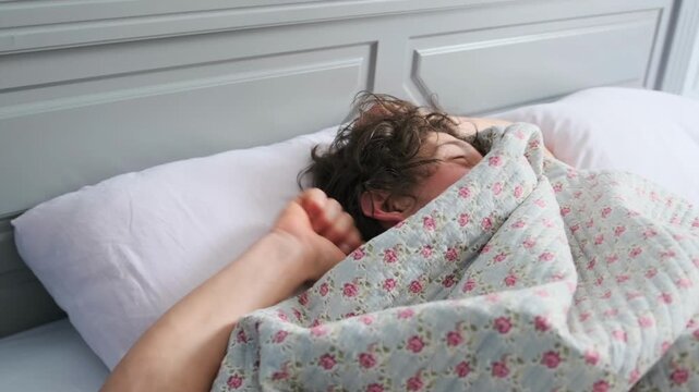 Man Awakens Gradually - Man Gently Moves As Morning Arrives - Daylight Softens As Man Awakens Beneath Floral Blanket - Man Slowly Stirs Beneath Colorful Cover As Morning Sun Shines Through Window