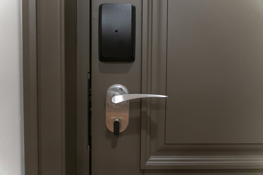Hotel room door with electronic key card lock and metal handle, modern security access system and minimalist interior design