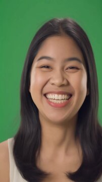 Happy young woman laughing openly on green screen background for joy reaction positive emotion and engaging social media video content