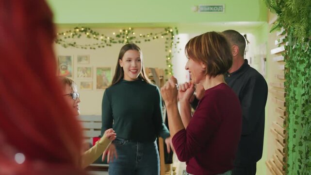 Group registration at festive reception desk, parents enroll child for community workshop while organizer and receptionist coordinate paperwork, friendly staff provide orientation and badges, greenery