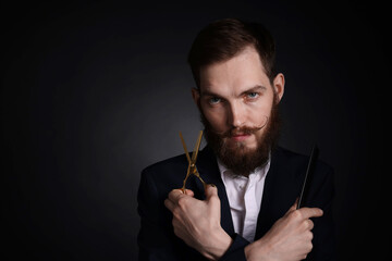 Man with barber's tools on black background. Space for text