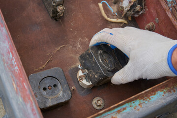 Work on dismantling outdated electrical equipment in a metal case,dismantling old electrical outlets inside an old rusty metal panel