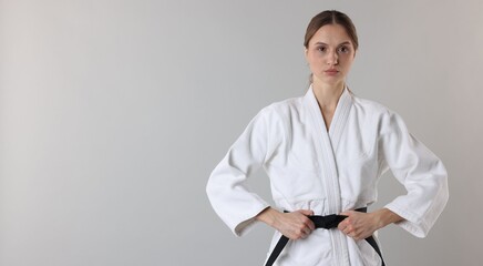 Karate fighter in uniform on light grey background, space for text