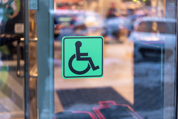 Green sign for disabled people on a shop window.