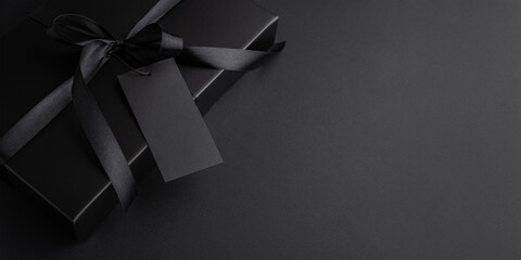 Black Gift Box with Satin Ribbon and Blank Tag. Luxury Packaging for Black Friday Promotion