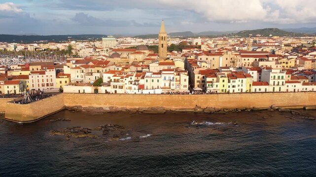 Aerial view of Alghero, Sardinia, showcasing its vibrant coastal scenery, historic buildings, and tranquil waters. Ideal for travel enthusiasts and explorers at sunset.