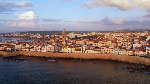 Aerial view of Alghero, Sardinia, showcasing its vibrant coastal scenery, historic buildings, and tranquil waters. Ideal for travel enthusiasts and explorers at sunset.