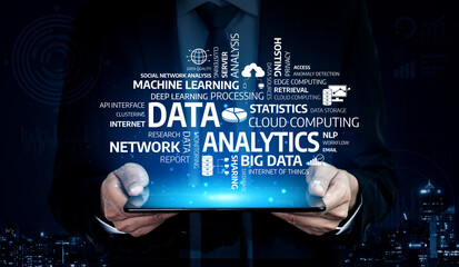 A businessman holds a tablet showcasing data analytics, with technology-related words prominently displayed, symbolizing cloud computing and big data concepts. Tessel