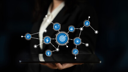 A business professional presents a tablet showcasing digital symbols around a target, symbolizing networking and analytics for successful growth strategies in modern business. Tessel