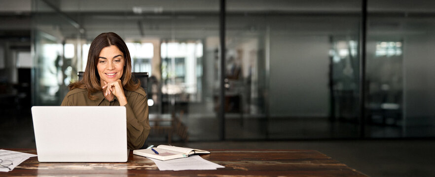 Happy busy mature business woman entrepreneur in office using laptop at work, smiling professional middle aged female company executive manager working looking at computer at workplace.
