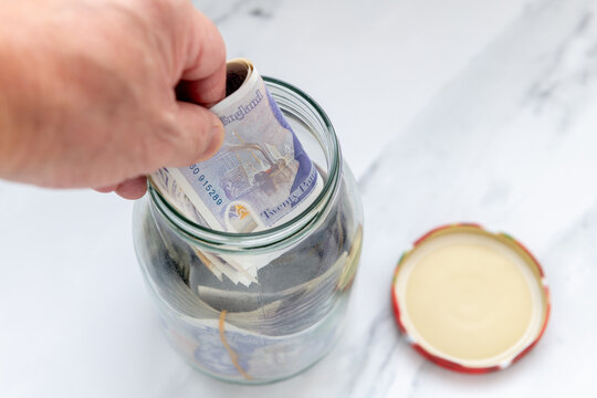 Person putting bank notes in a jar.