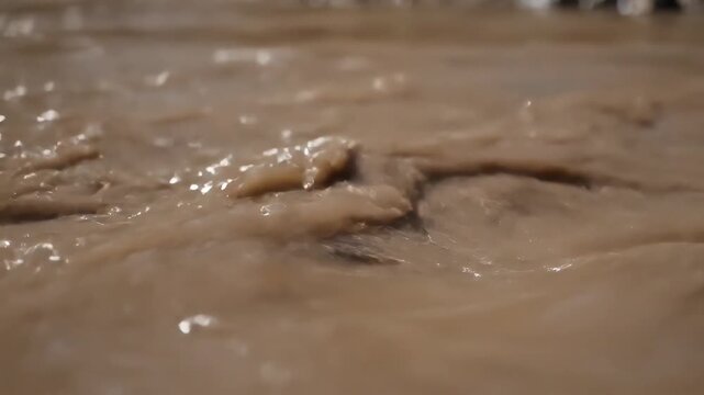 Closeup of muddy water with ripples and splashes showcasing the texture and movement of the liquid.