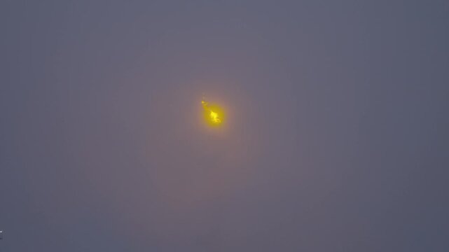 Industrial smokestack flaring off excess gas in fog.