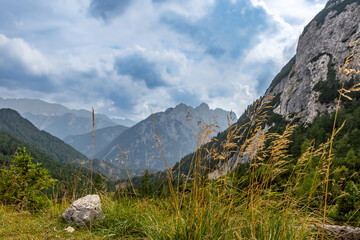Vrsic Pass shows beautiful mountain landscapes with grass and rocks under a cloudy sky, perfect for nature lovers and travelers.