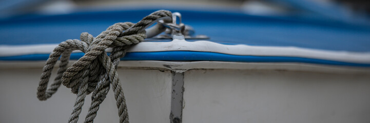 Panorama of rope and knot on the bow of a small blue dinghy