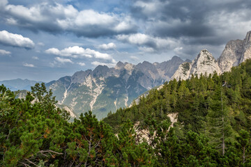 Vršič Pass shows a view of mountains and trees under a cloudy sky in Slovenia. This location is...