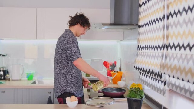 Young chef flipping, Caucasian guy making breakfast, Young man seasoning and turning over omelette with flair, Bright kitchen scene showing young man expertly flipping and seasoning omelette