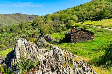 Small stone house in an idyllic landscape of green meadows and high mountains, Spain.