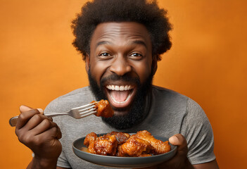 A smiling black man eats meat in sauce with a fork.