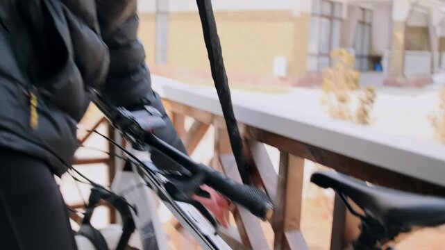 Man secures bike, Man locks bicycle carefully outside, Man firmly fastens his bicycle on balcony in cold weather, Male individual diligently secures his bicycle with lock during cold outdoor