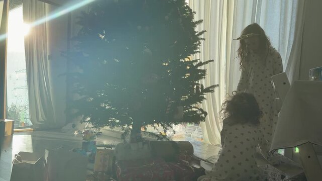 Two Girls Unwrapping Christmas Gifts at Home on New Year Morning