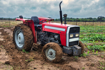 agricultural tractor in deep mud on a farm field, agricultural work in challenging, wet conditions, drip irrigation system