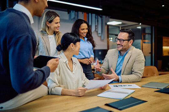 Group of diverse business people engaging in a lively discussion during a team meeting in a modern office boardroom