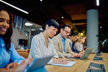 Diverse business professionals collaborating and focusing on work tasks in a contemporary office setting, showing dedication and teamwork
