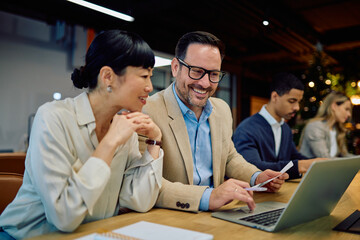 Diverse business professionals working together, discussing ideas, and analyzing data on a laptop in a contemporary co-working space