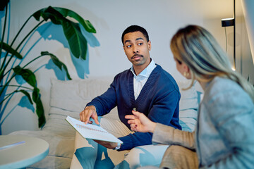Two diverse professionals collaborating and discussing business strategy, analyzing financial reports together in a modern office space